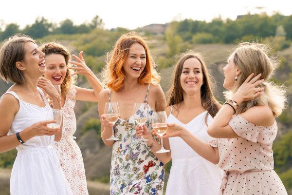 group of women laughing and drinking wine